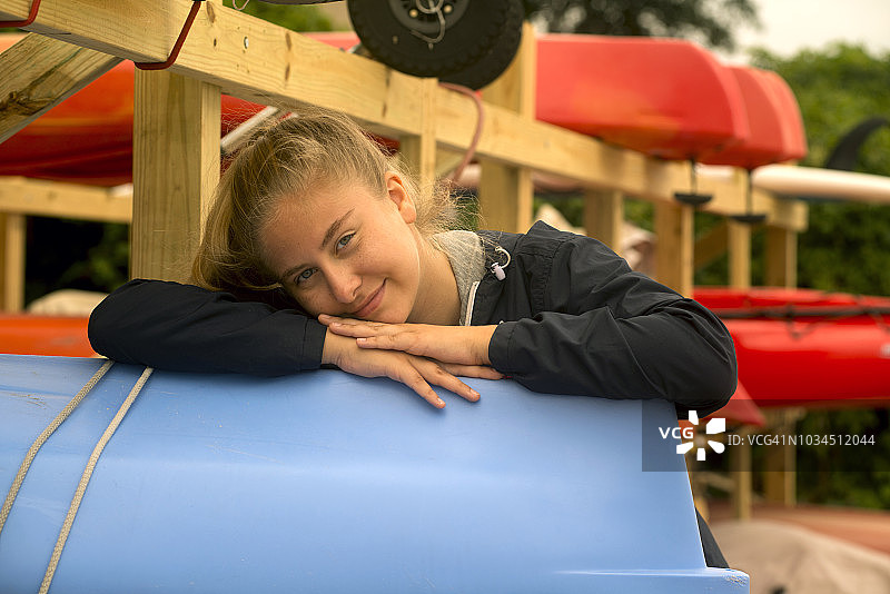 金色头发少女在皮划艇架子旁摆姿势图片素材