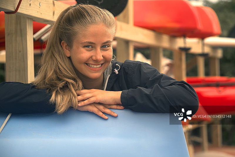 金色头发少女在皮划艇架子旁摆姿势图片素材