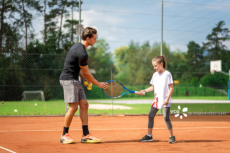 年轻男子教女孩打网球图片素材