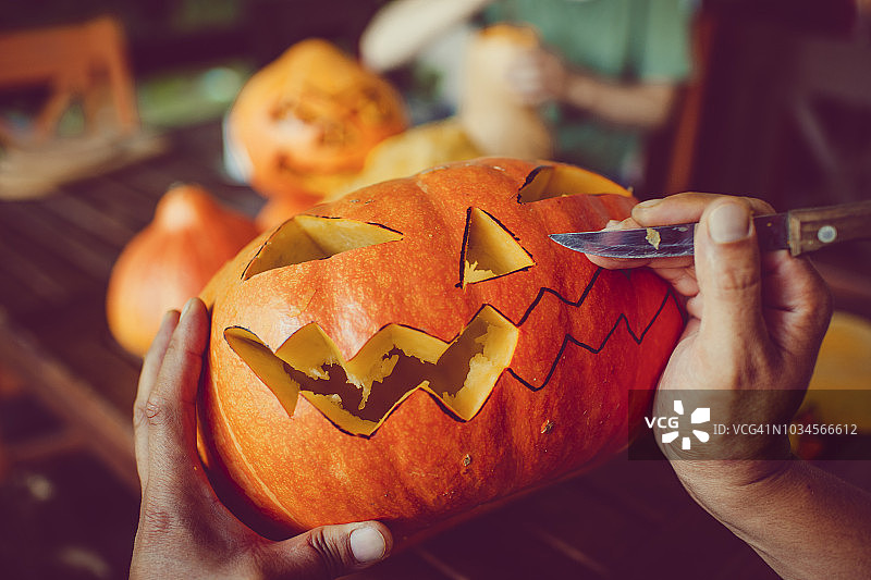 万圣节男子在南瓜上雕刻恐怖面孔图片素材