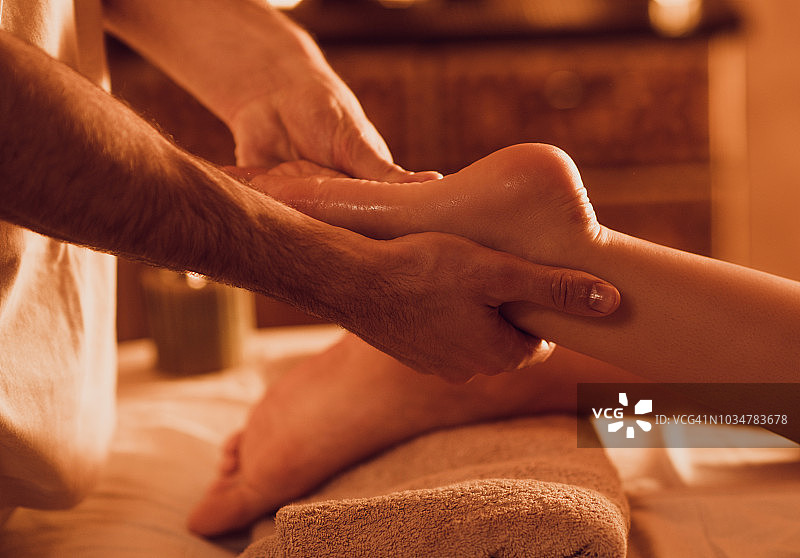 一位在水疗中心为顾客按摩脚部的身份不明的理疗师特写镜头图片素材