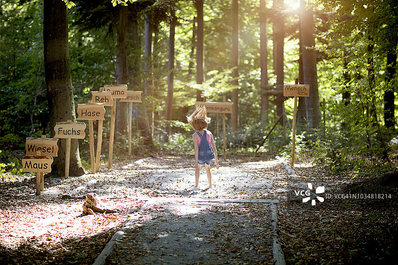 女孩在森林里完成跳远后落在沙地上图片素材