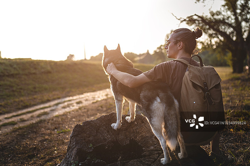 男子与哈士奇犬欣赏日落图片素材