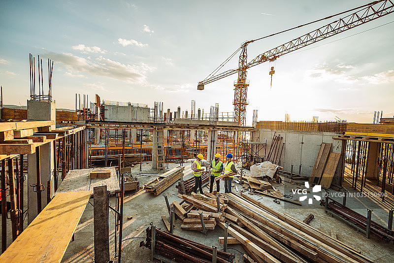 建筑工地，三名工程师和新摩天大楼顶部的起重机图片素材