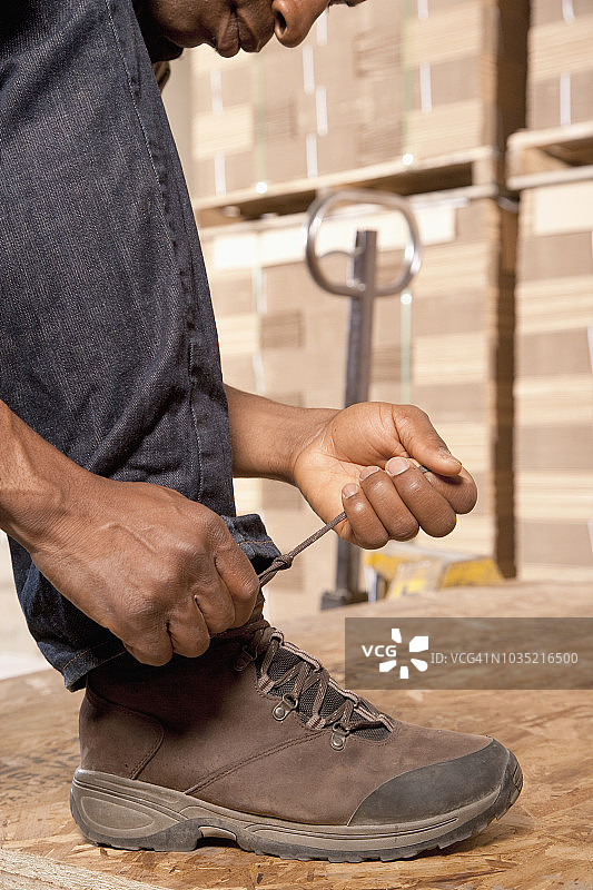 在仓库里系鞋带的黑人男子图片素材