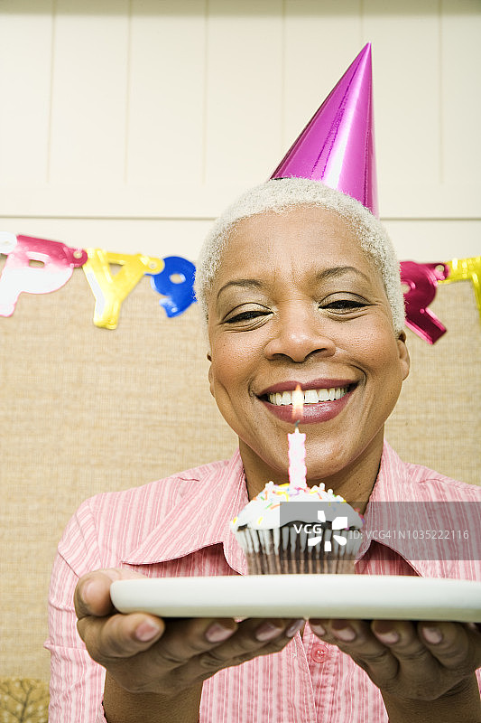 在生日派对上拿着纸杯蛋糕的非洲裔女人图片素材