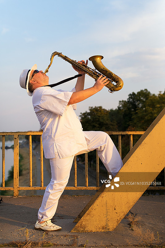 优雅男士在桥上吹奏萨克斯图片素材