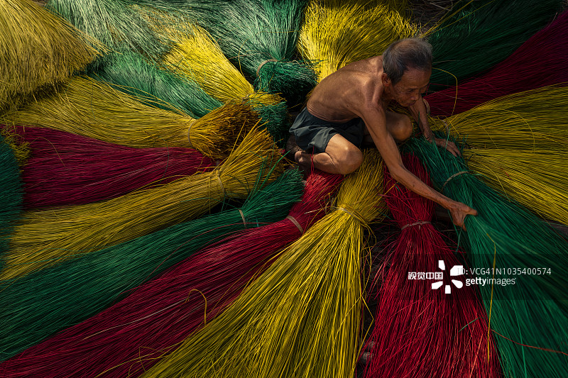 越南同塔省定安传统工艺村，整理彩色竹垫的老年越南男人图片素材