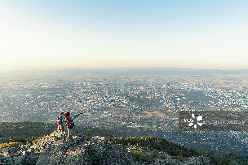 情侣站在山顶指向城市图片素材