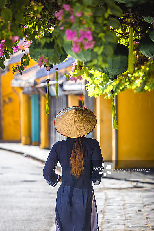 身穿传统服饰、头戴斗笠的越南女人游览越南会安古镇图片素材