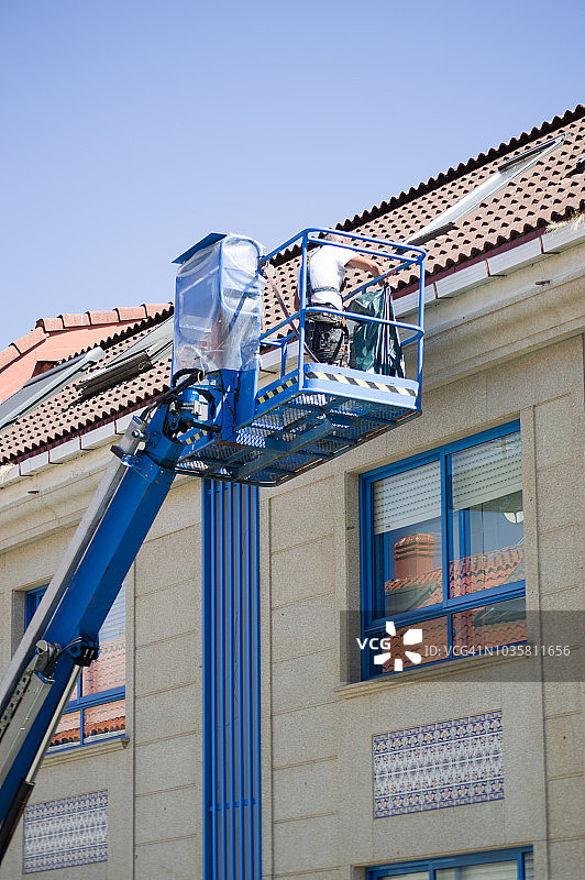 用液压起重机清洁建筑物排水沟图片素材
