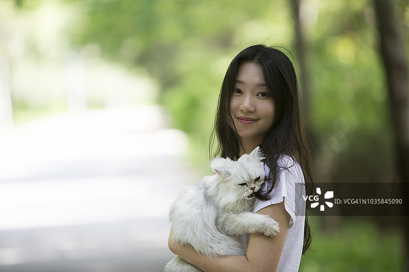 年轻的亚洲女人在公园里和猫玩耍，人与动物的关系图片素材