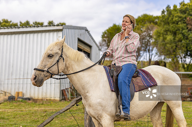 中年妇女骑马时使用手机图片素材