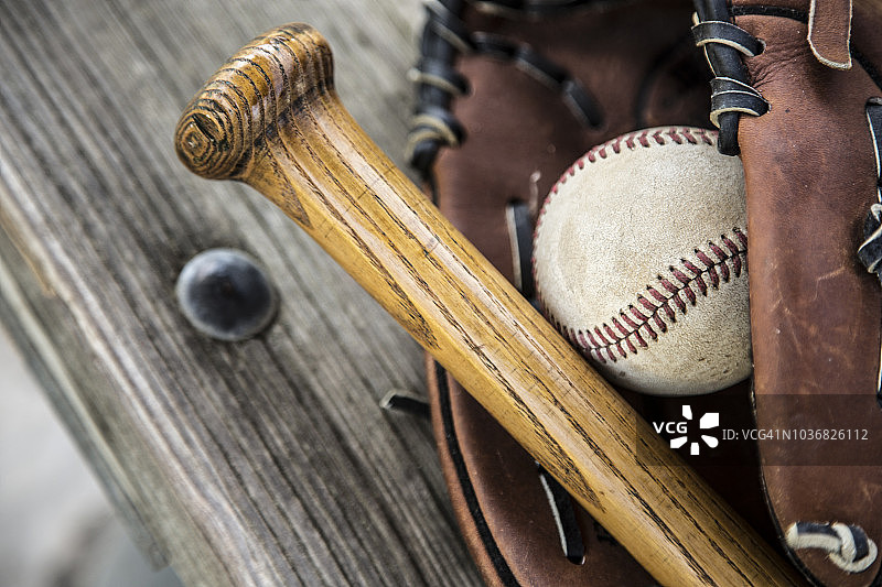 棒球赛季开始了：球棒、手套和球在休息区长椅上图片素材