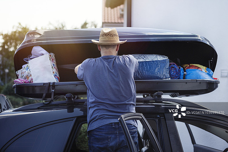 男人在度假前将行李装入车顶行李箱图片素材