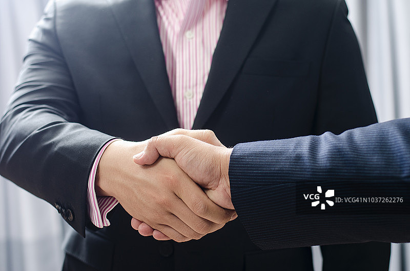 合同签订后两位同事紧握双手的特写图片素材