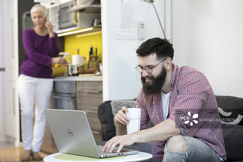 母亲和儿子在客厅使用笔记本电脑图片素材