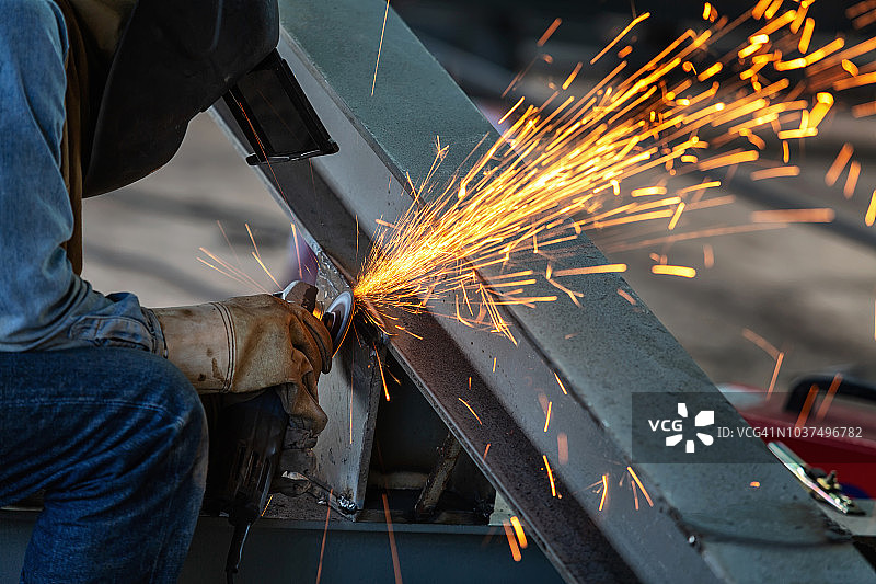 工厂里，电焊工用电动砂轮打磨钢结构，火花四溅图片素材