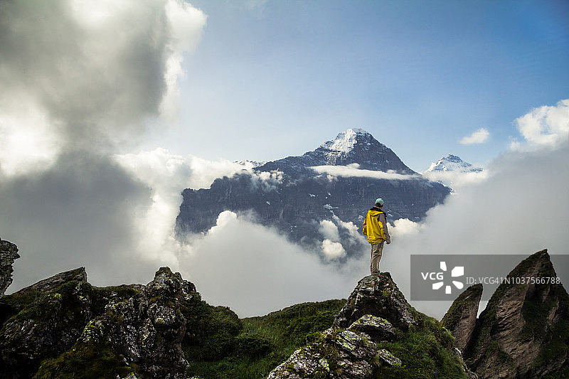 身穿黄色夹克的徒步者俯瞰格林德瓦山谷图片素材