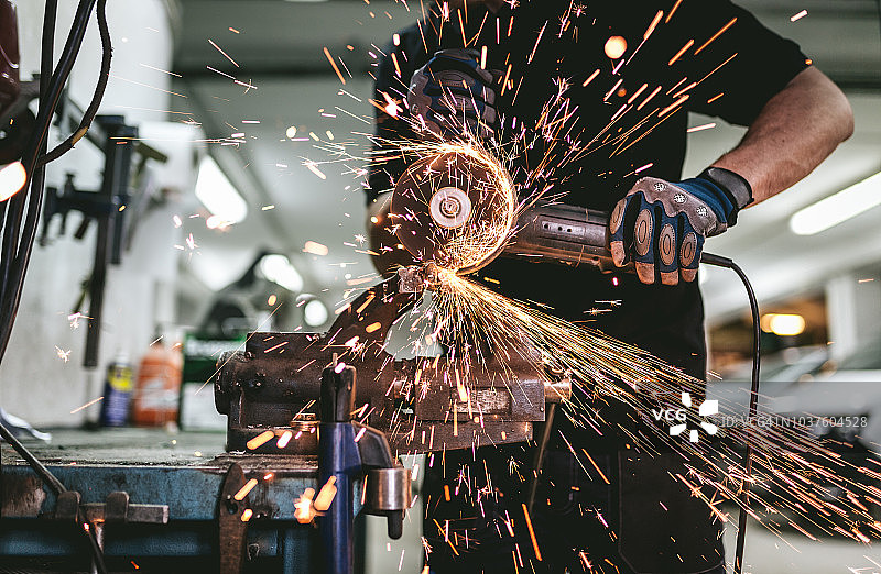 重工业工人用角磨机切割钢材图片素材