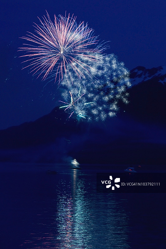 水面上的烟花与背景中的山脉图片素材