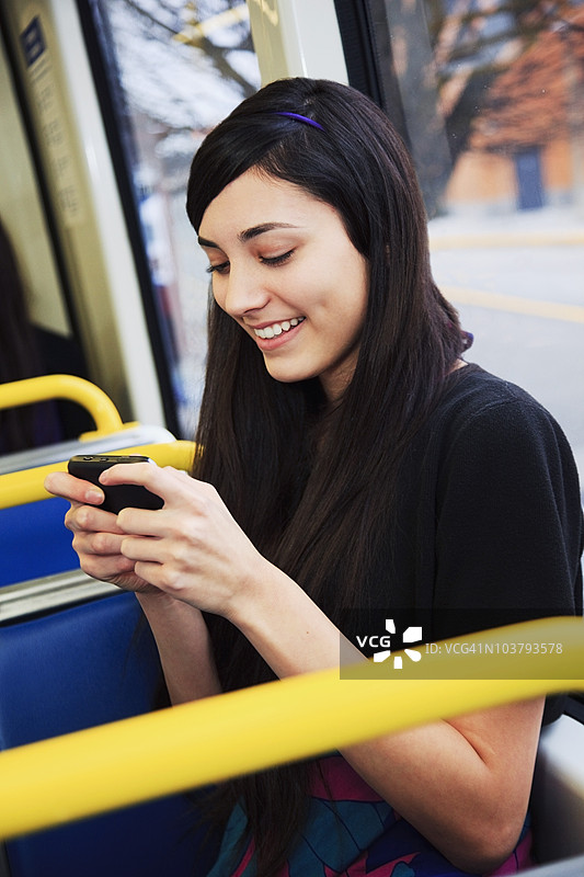 一名少女在公共交通上坐着使用手机图片素材