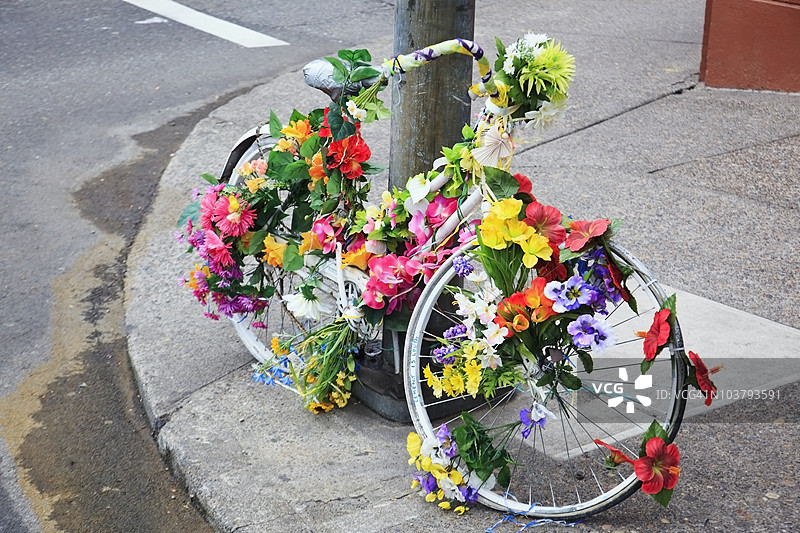 一辆装饰着花朵的自行车靠在柱子上图片素材