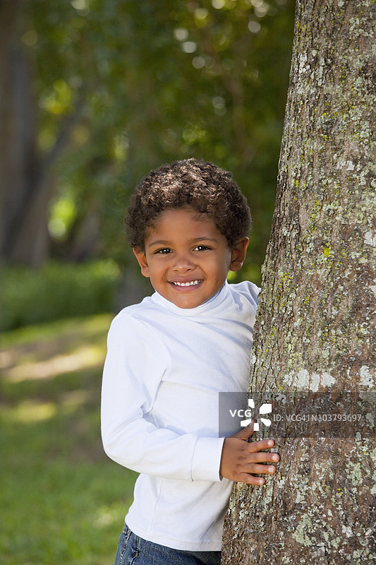 一个男孩站在树旁图片素材