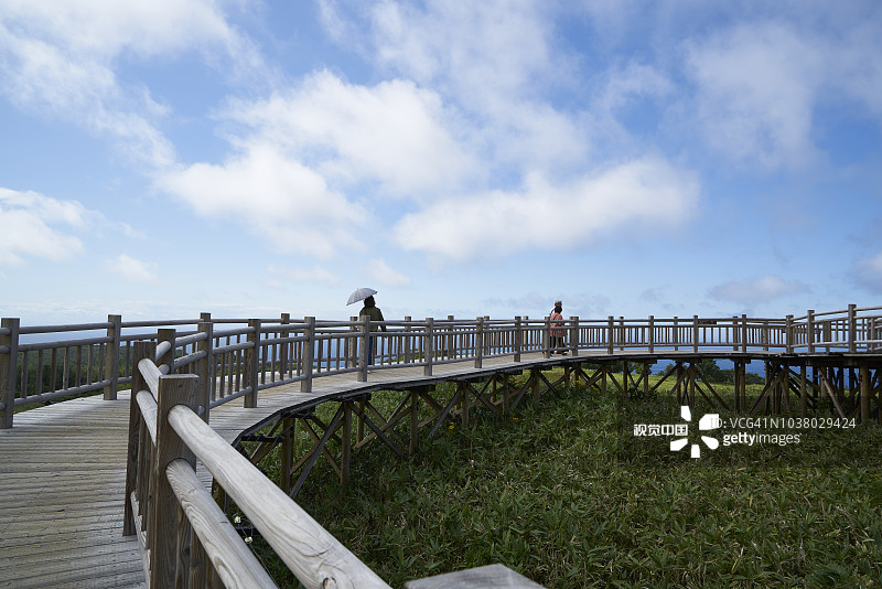 游客在知床国立公园的木制高架木板路上欣赏五知床湖、鄂霍次克海和周围群山的景色图片素材