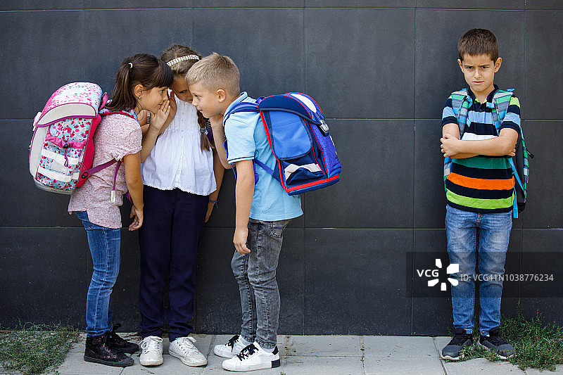 不开心的男孩被学生朋友们议论图片素材