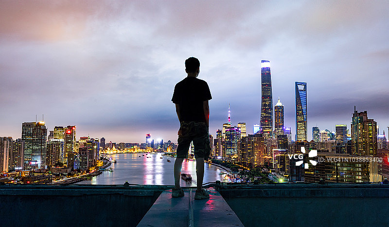 年轻男子在屋顶眺望上海中央商务区图片素材