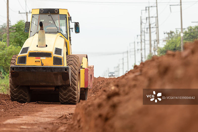 在高速公路建筑工地工作的黄色振动压路机图片素材