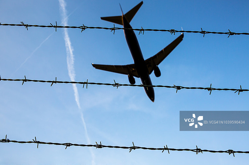 勃兰登堡舍内费尔德机场上空的带刺铁丝网和客机图片素材
