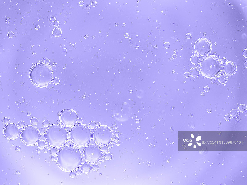 柔和紫色液体背景上的气泡和水滴抽象形状和纹理特写图片素材