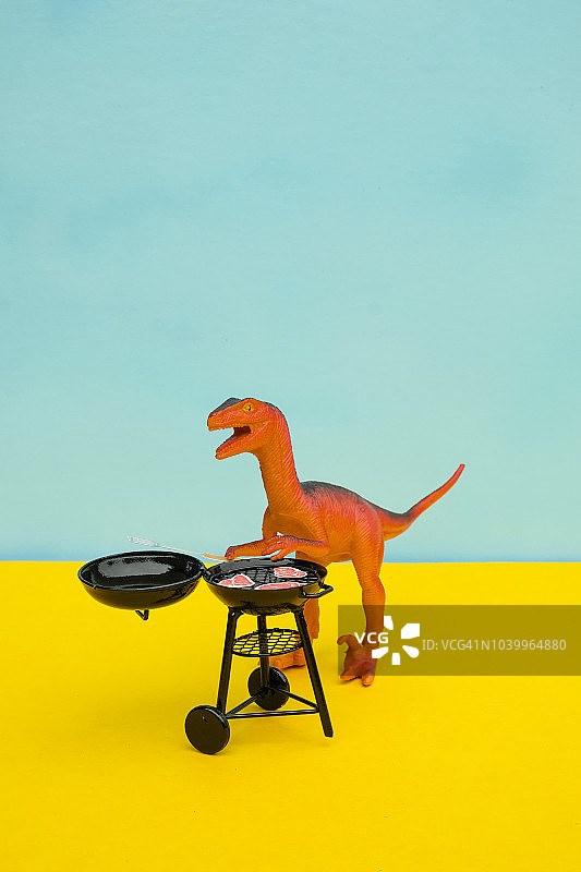有趣的彩色玩具恐龙概念场景-烧烤食肉动物图片素材