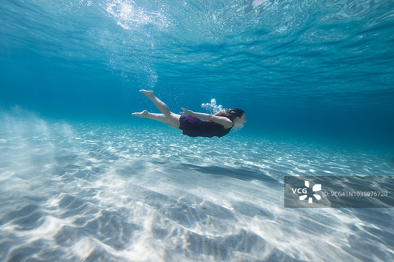 在水中游泳的紫色连衣裙年轻女人图片素材