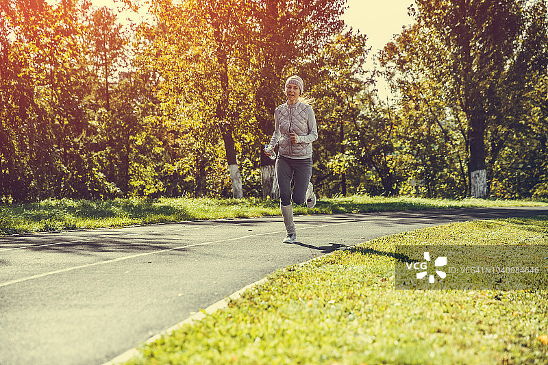 在体育场跑道上跑步的年轻女人图片素材