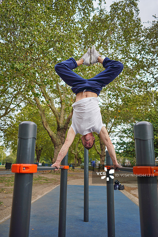 年轻的运动员在双杠上做倒立图片素材