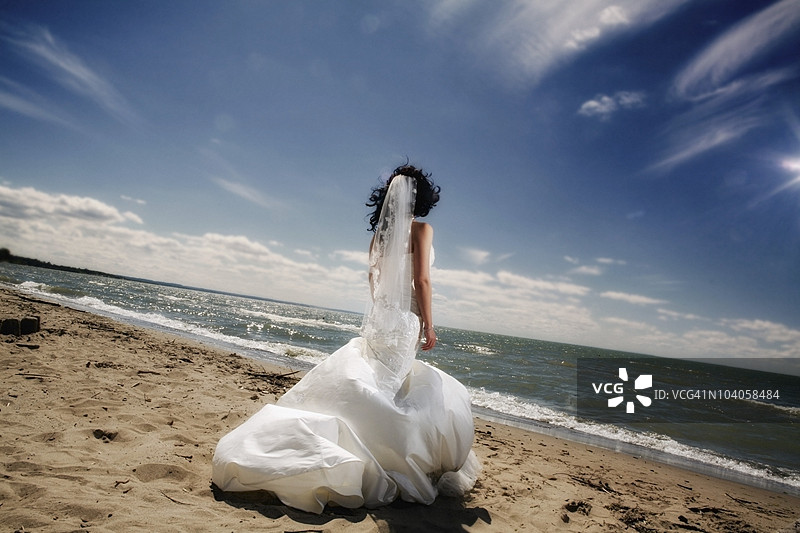 一位新娘站在海滩上凝视着海洋图片素材