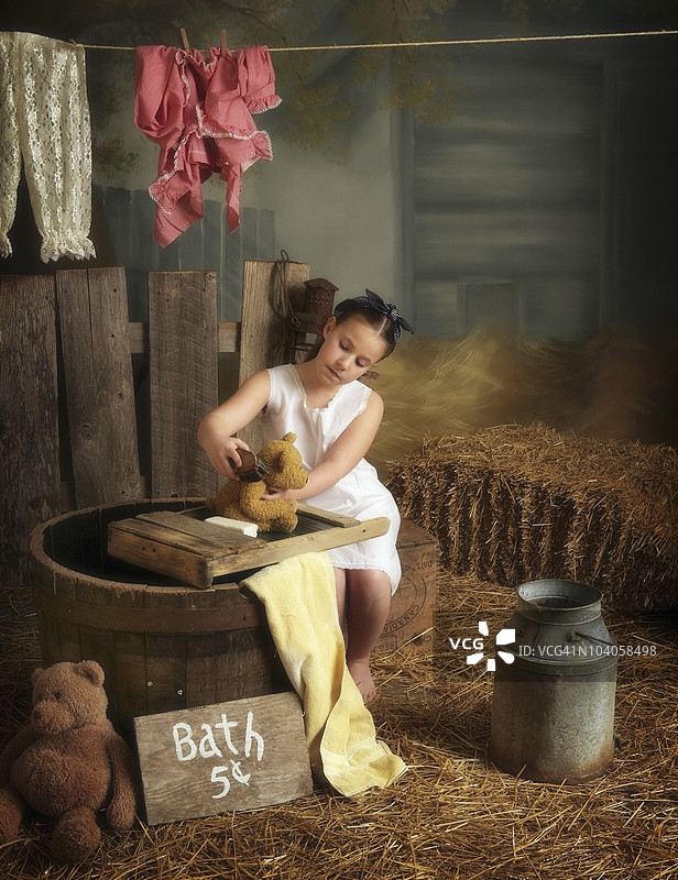 一个女孩在谷仓里洗她的泰迪熊图片素材