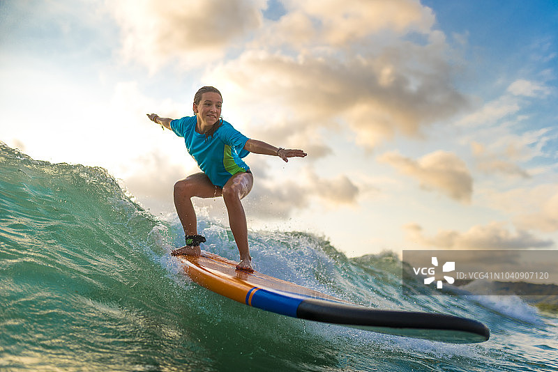 在日落时分冲浪的年轻女孩图片素材