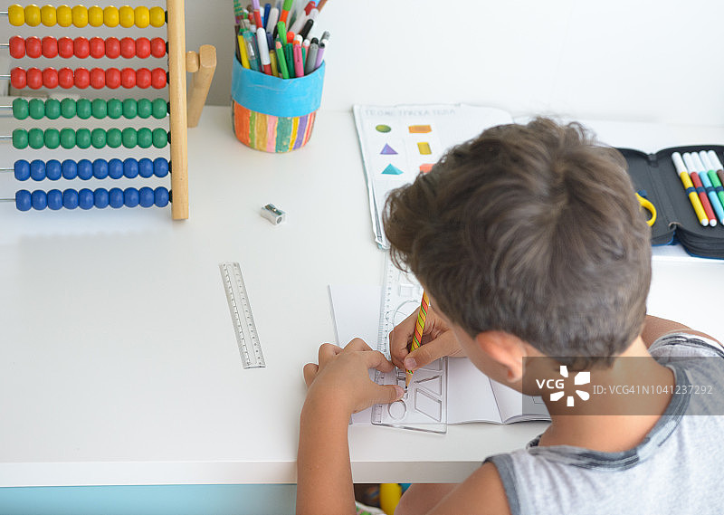 坐在桌旁做学校作业的漂亮男孩图片素材