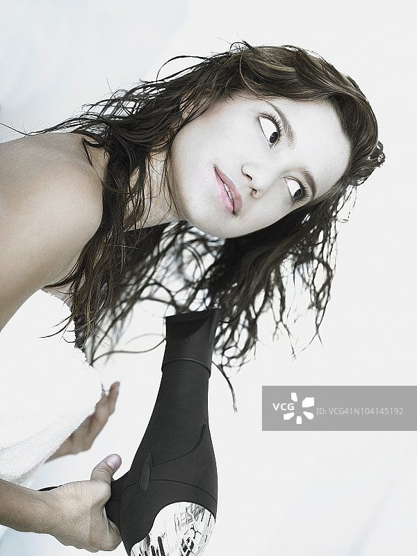 用吹风机吹干头发的年轻女子侧面照图片素材