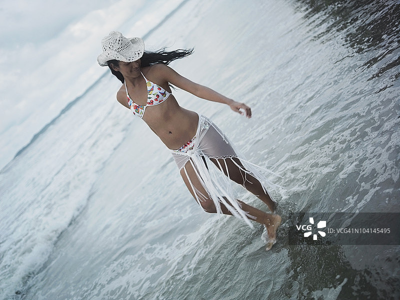 在沙滩上散步的年轻女人图片素材