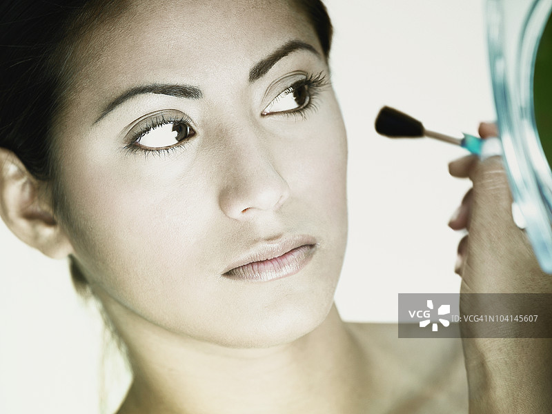 年轻女性用化妆刷化妆的特写镜头图片素材