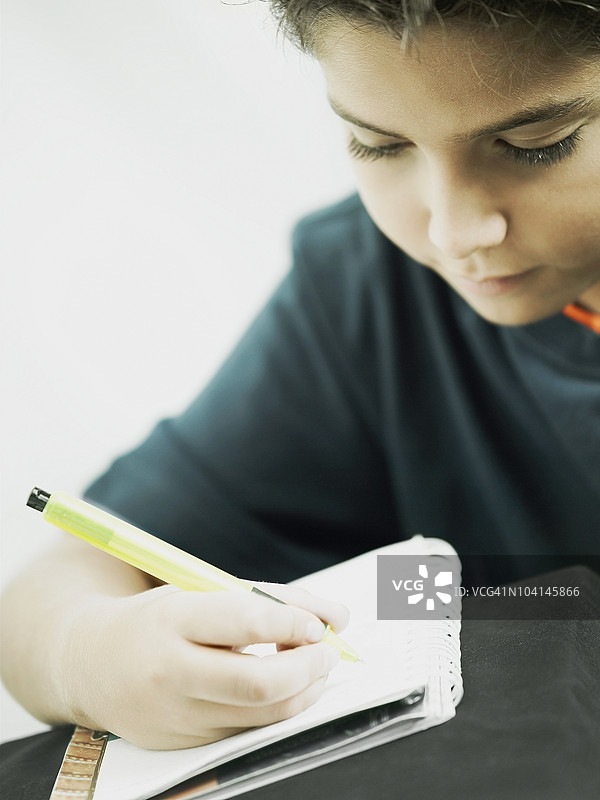 男孩在笔记本上写字的特写镜头图片素材