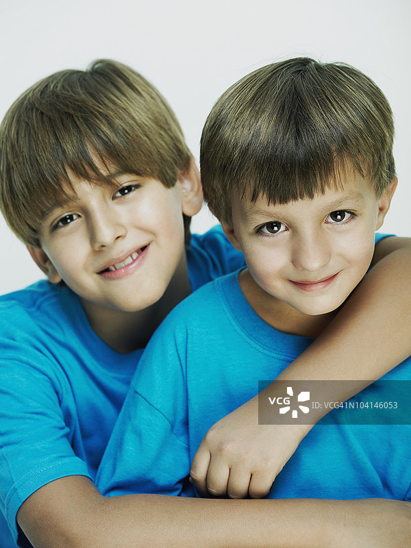 一个男孩把手臂搭在他兄弟的肩上图片素材