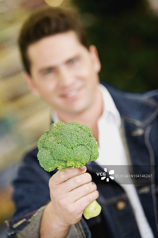 手持西兰花的年轻男人肖像图片素材