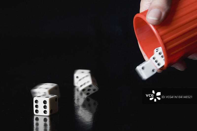 一个人用杯子掷骰子的特写镜头图片素材