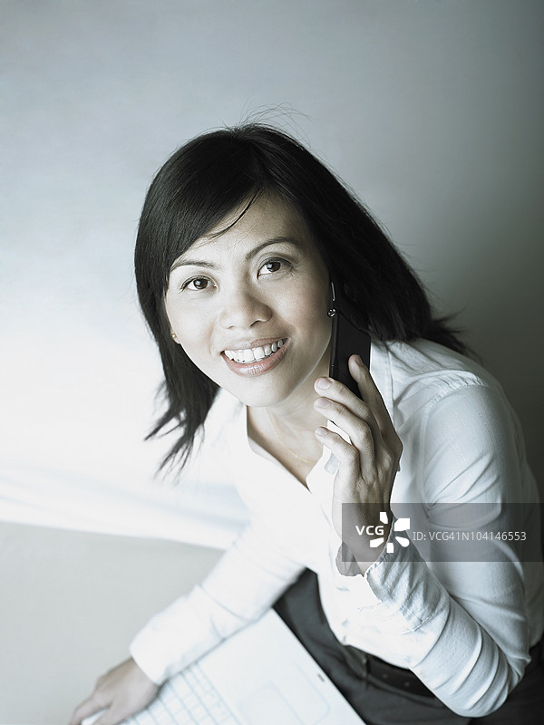 一位中年女性微笑着使用手机的肖像图片素材